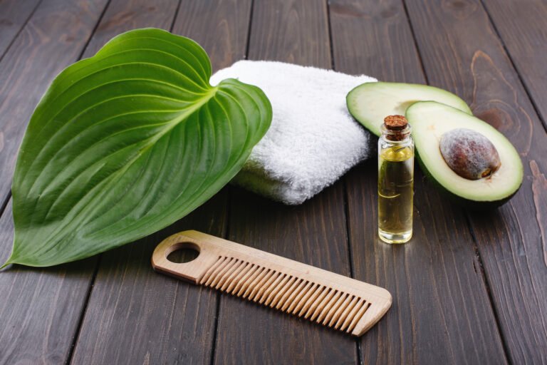 White towel, avocado, little glass bottle and wooden comb for ha